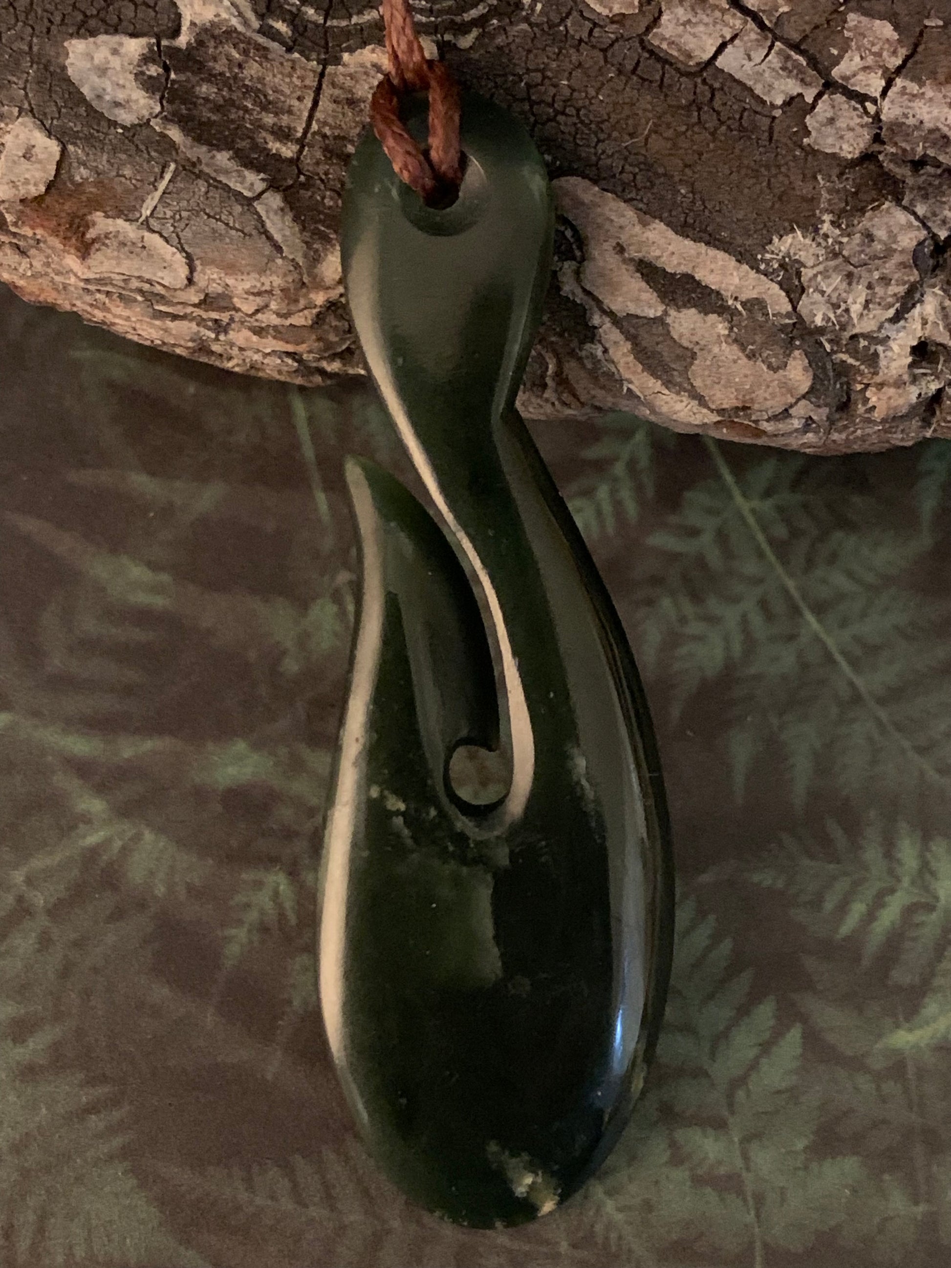 showing reverse of Maori made hei matau fish hook from New Zealand Pounamu greenstone jade